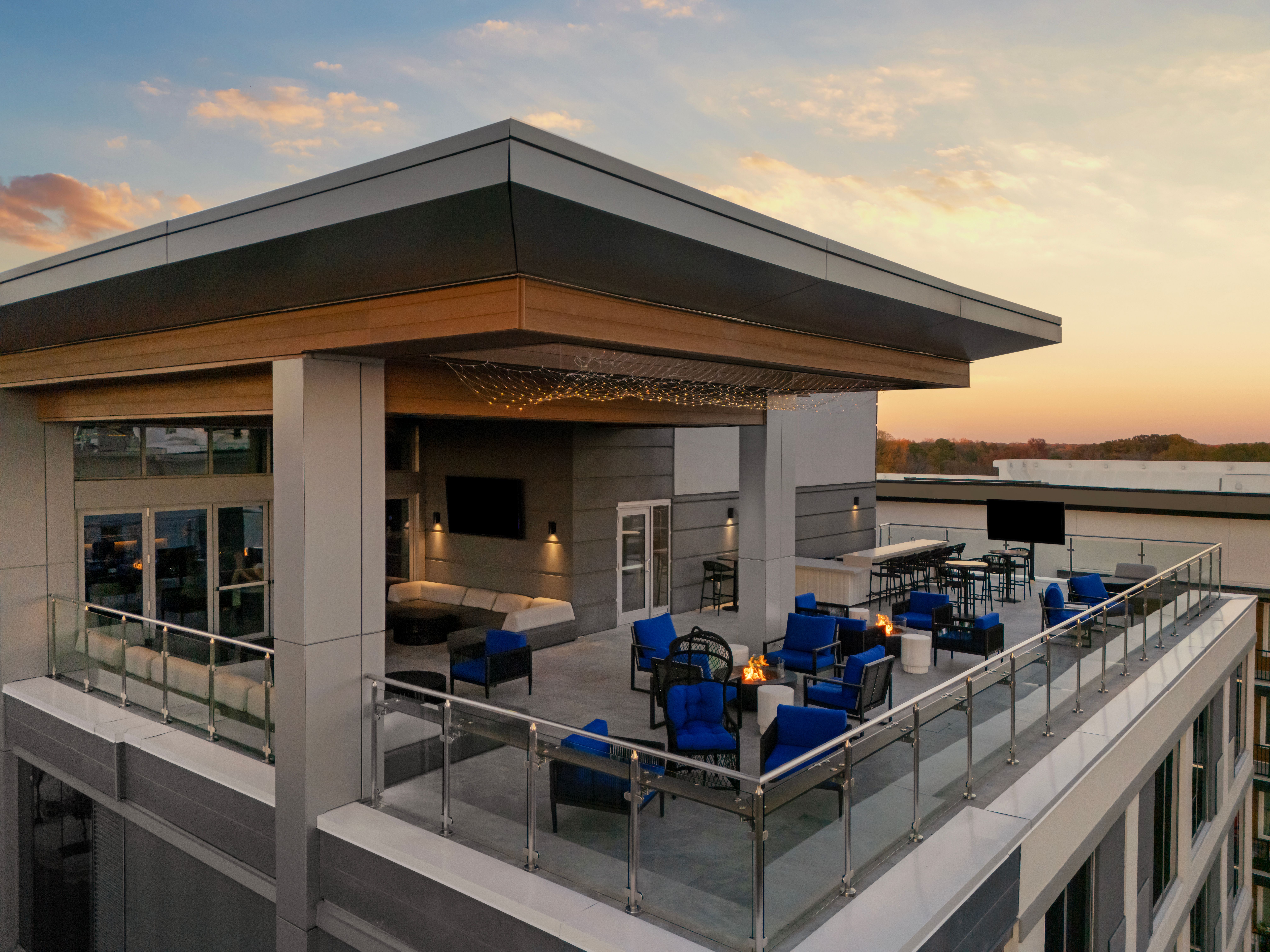 Rooftop bar at AC Hotels Raleigh at sunset, featuring modern outdoor seating, fire pits, and panoramic city views.