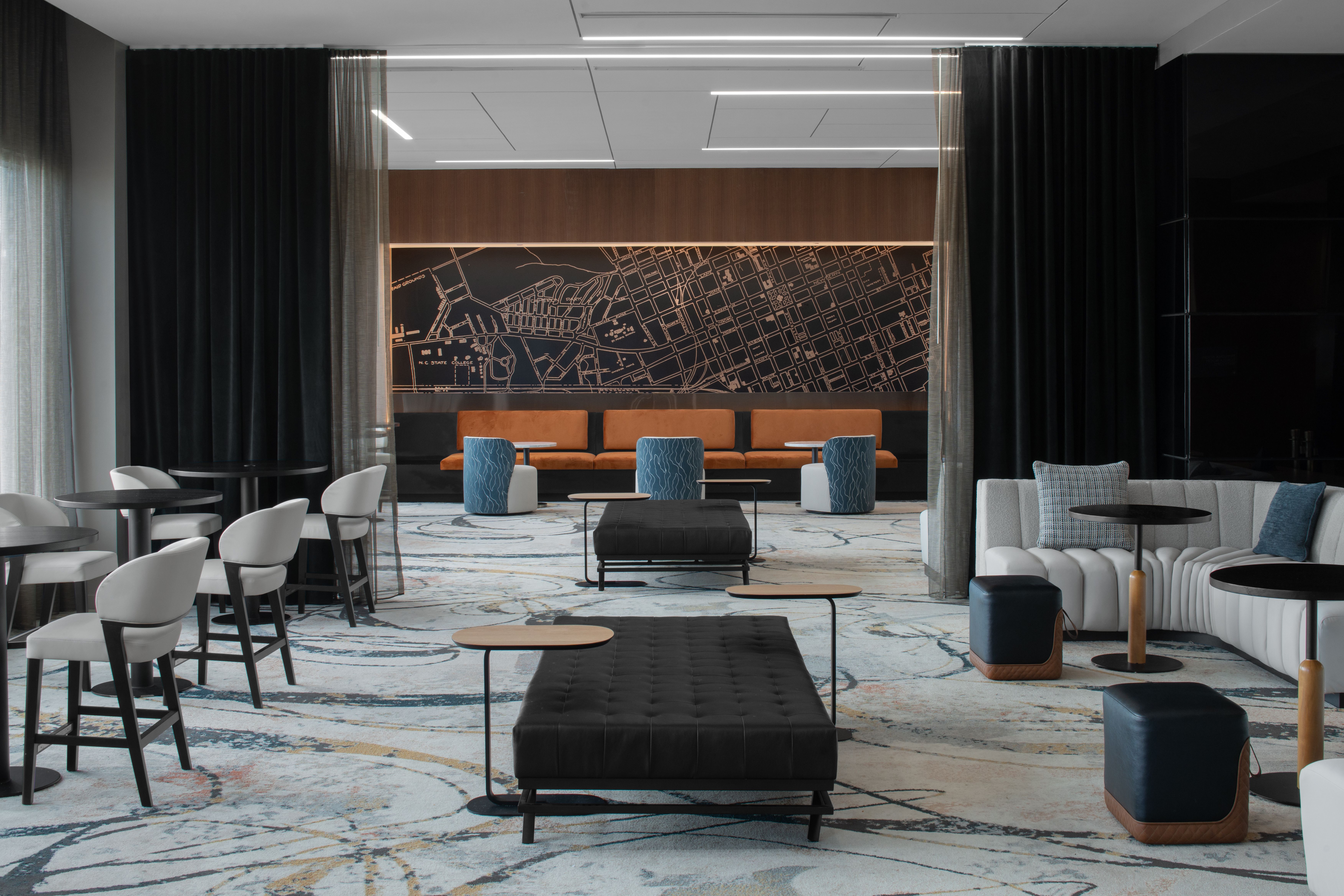 A stylish lounge area at AC Hotels Raleigh, with contemporary furniture, a city map mural, and an inviting ambiance.