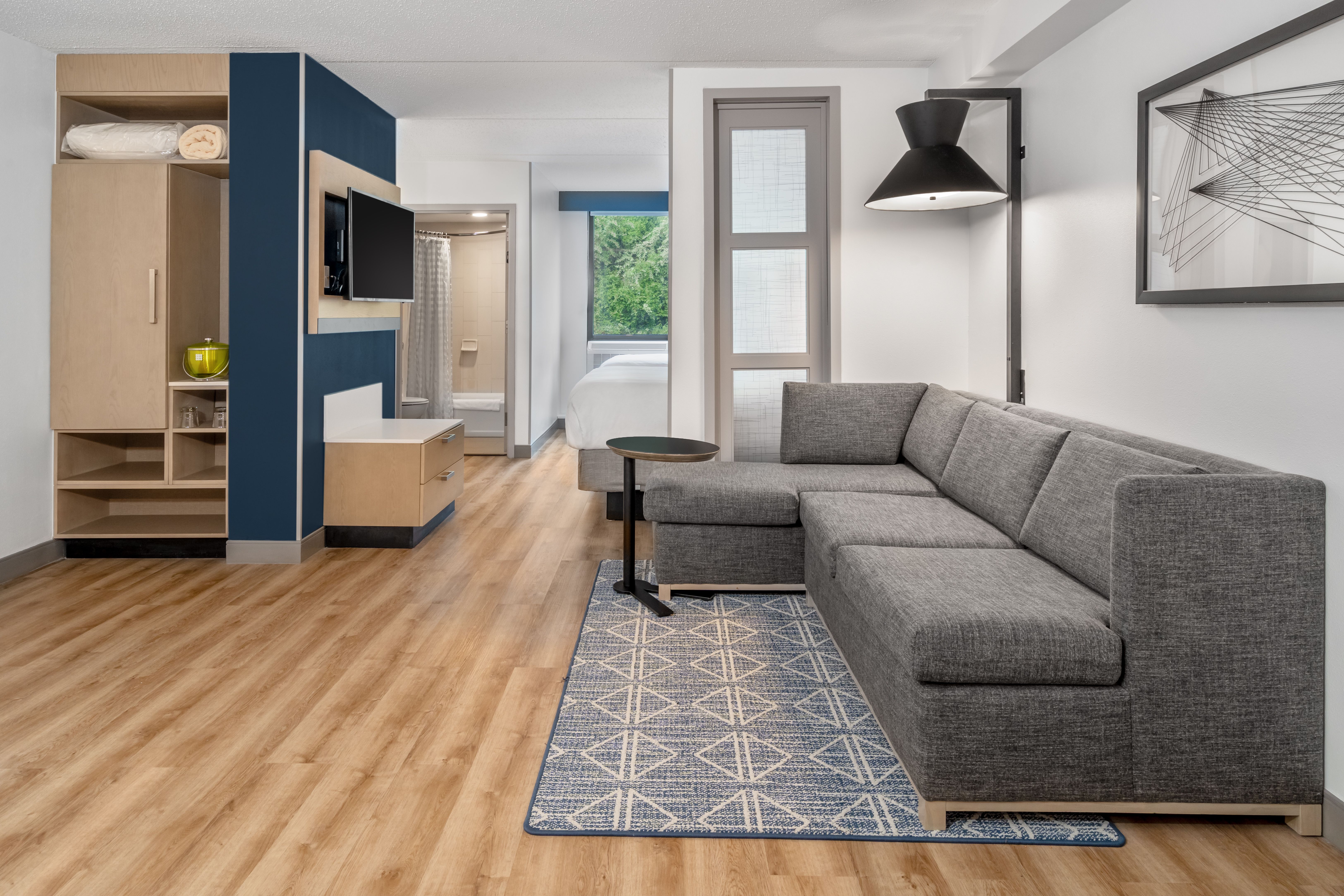 Guestroom in Hyatt Place Mystic, with grey sofa, and blue accent walls and carpet